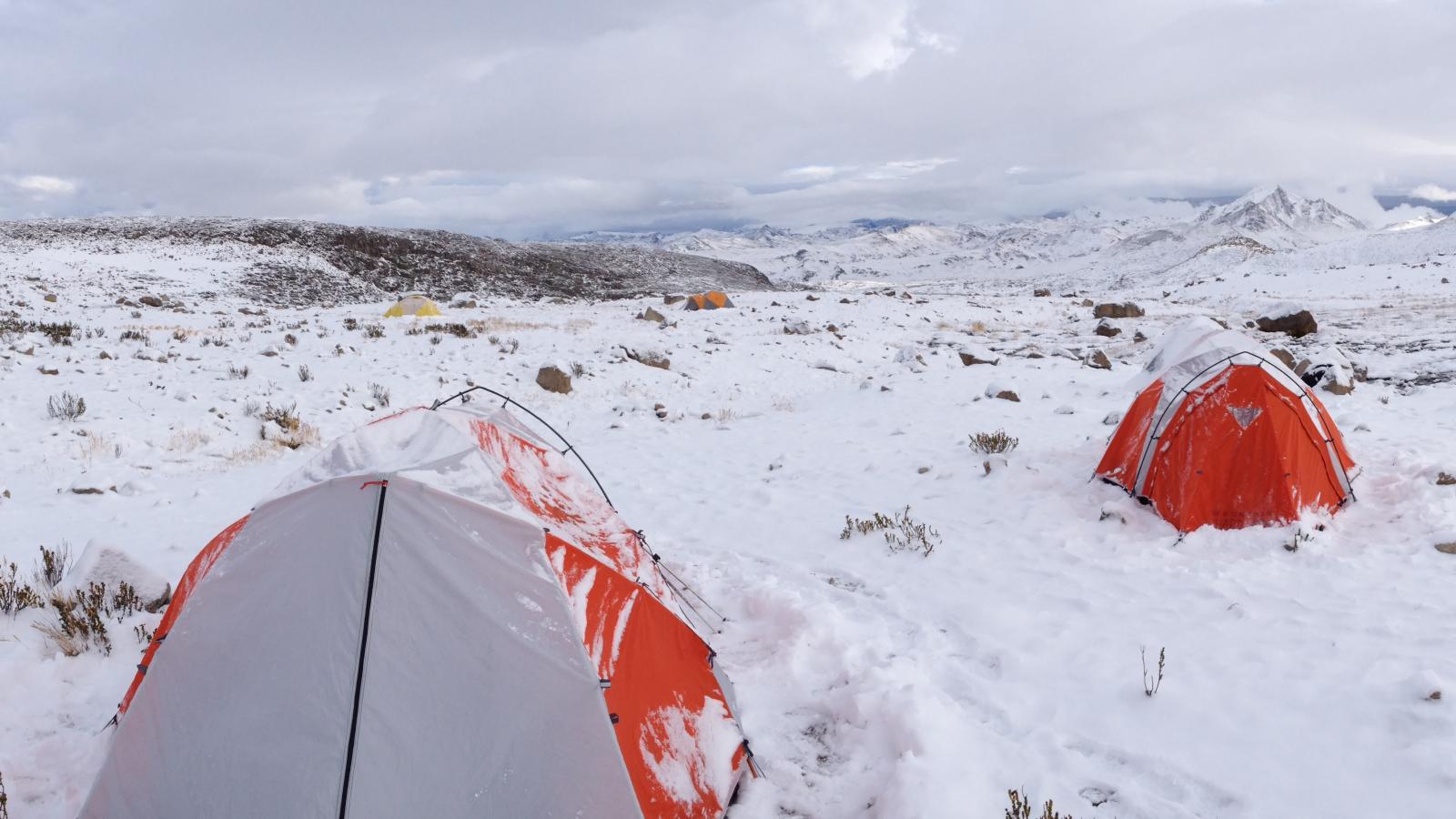 Tents in snow-covered terrain with mountains in background