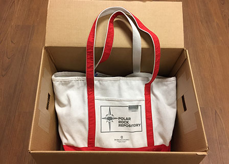 A rock box from the Polar Rock Repository. A box with a canvas bag in it with red straps and text on the bag states Polar Rock Repository with an their logo..