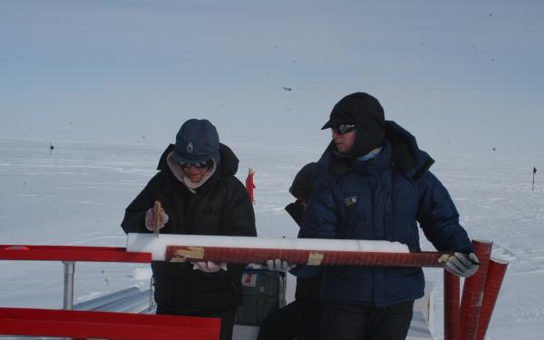 2 team members collaborate in the field. The landscape is gray and snowy 