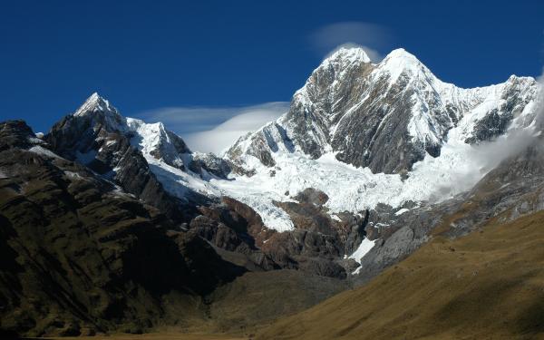 Landscape of mountains with snow covered caps. The sky is a sunny and bright blue