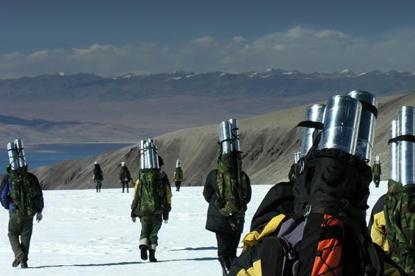 A group of people carry ice cores across the snowy landscape