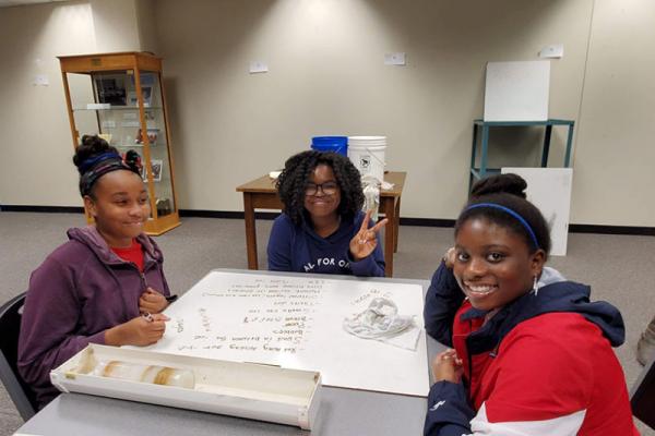 three Students sit around a table and make their own ice cores at the Byrd Center