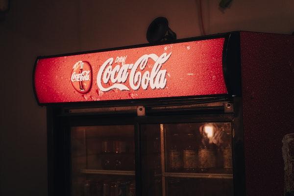 Coca-Cola Vending Machine with red sign back-lit in a dark room.