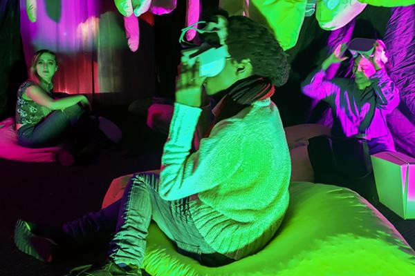 Students explore the art installation "Un-becoming Carbon,". Photo credit Amy Youngs. Students sitting in bean bags looking at VR headsets