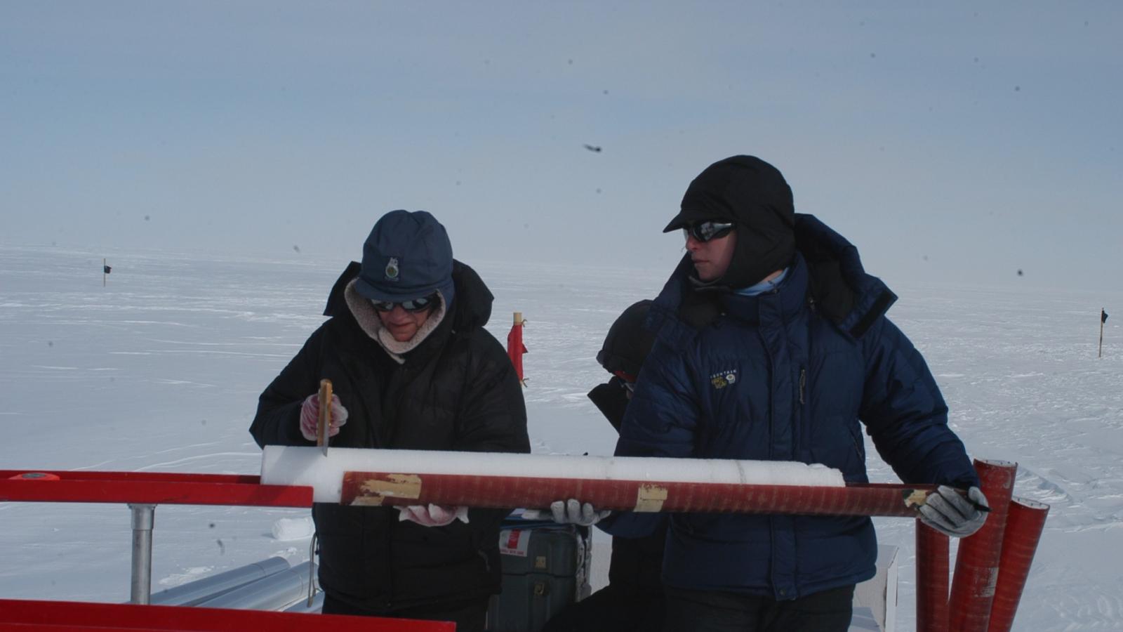 2 team members collaborate in the field. The landscape is gray and snowy 